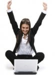Excited woman raising her arms while sitting with a laptop, representing success in meeting state requirements for pediatric board certification.