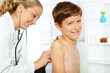 Pediatrician examining a smiling child, illustrating the role of pediatricians in healthcare.