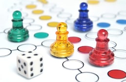 Game pieces and dice on a board representing that Pediatric Board Questions are like a game