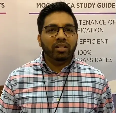 Groups Man in glasses and checkered shirt standing in front of a sign featuring educational content related to maintenance of certification and efficient pass rates.