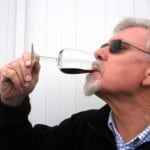 Man drinking a glass of wine, celebrating passing the pediatric boards.