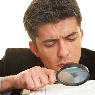 Man using a magnifying glass representing the importance of focusing on details in Pediatric Board Exams