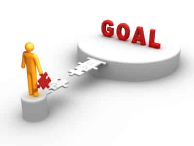 Figure placing a puzzle piece on a path leading to the word 'GOAL', symbolizing achieving objectives in board exam preparation.