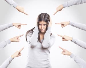 Woman surrounded by pointing fingers representing the advice to avoid regrets when preparing for Pediatric Board Exams