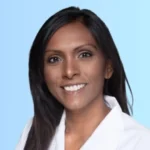Why AAP Prep Questions are NOT the Best Study Questions Smiling woman with long dark hair in a white coat against a light blue background. Professional portrait ideal for a healthcare or business profile.