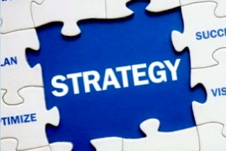Home Puzzle pieces with the word strategy centered in blue highlighting planning teamwork and success Keywords like brand optimize and vision surround the central concept