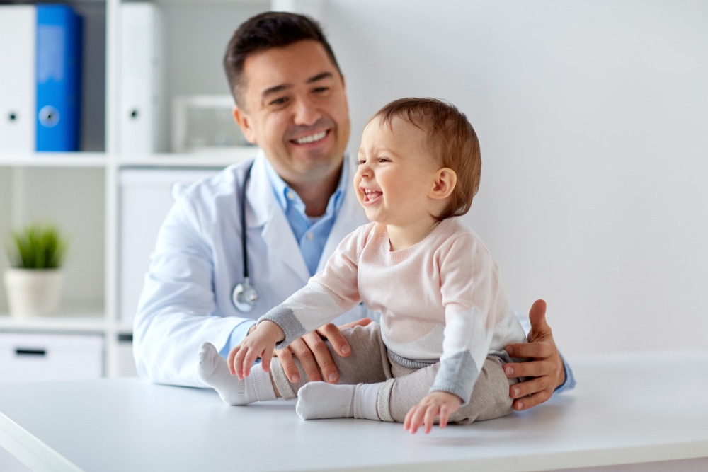 Pediatrician examining a happy baby during a check-up, related to the MOCA-Peds Exam guide on Pediatrics Board Review.
