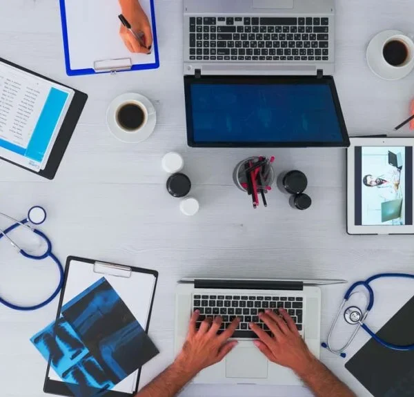 Shared clinical workspace with laptops, charts, and exam materials illustrating how proximity to high-yield resources can improve pediatric in-training exam scores.