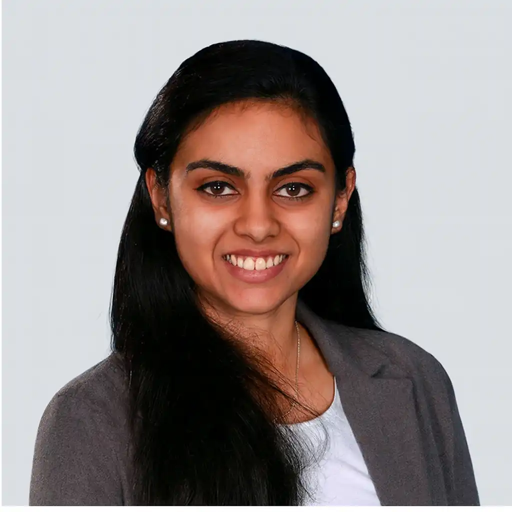 Home Dr. Varsha Raghavan smiling confidently, wearing a dark blazer over a white top.